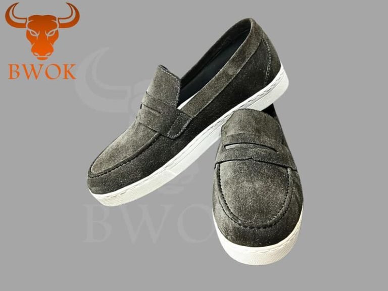 Pair of suede grey men’s loafers with white soles on grey background