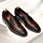 Elegant brown leather loafers shoes on light wooden surface