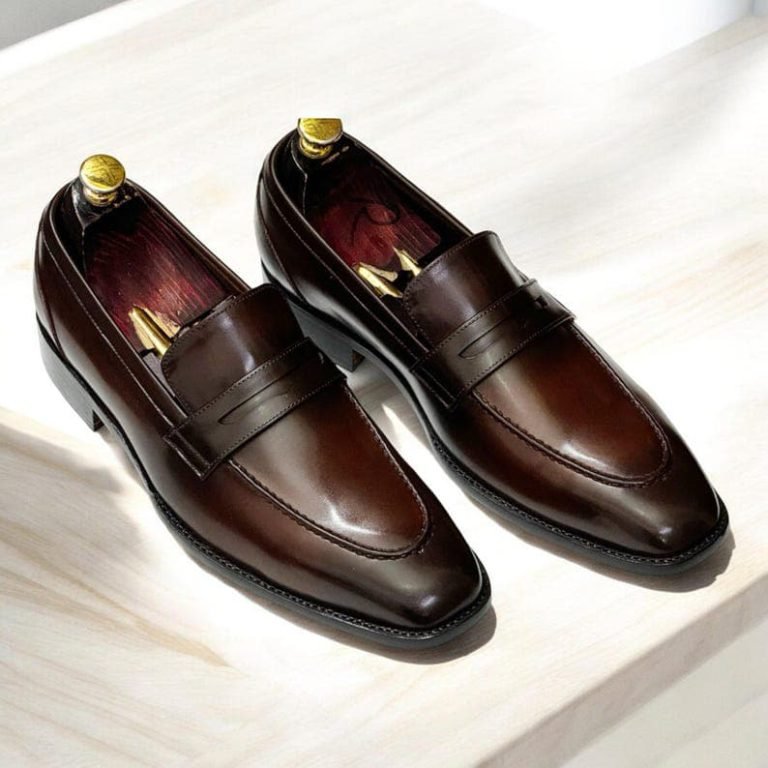 Elegant brown leather loafers shoes on light wooden surface