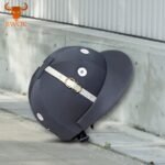 Black equestrian helmet with silver vents and chin strap placed on concrete