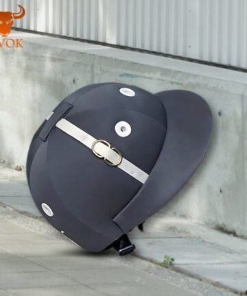 Black equestrian helmet with silver vents and chin strap placed on concrete