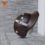 Dark brown horse riding helmet with chin strap on gray tiled background